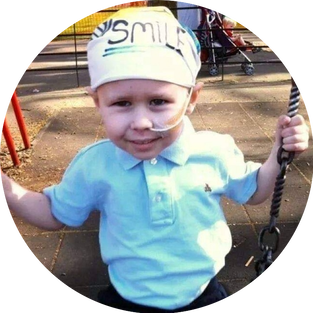 Mitchell Huth on a swinn in a park_Mitchell Huth on a swing in a park_smiling to camera_Mitchells Miracles_Neuroblastoma cancer charity for the UKsmiling to camera_Mitchells Miracles Neuroblastoma cancer charity