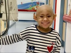 Young cancer patient_Maya Nash_in hospital receiving treatment_smiling to the camera_Mitchells Miracles_UK Neuroblastoma childrens cancer charity