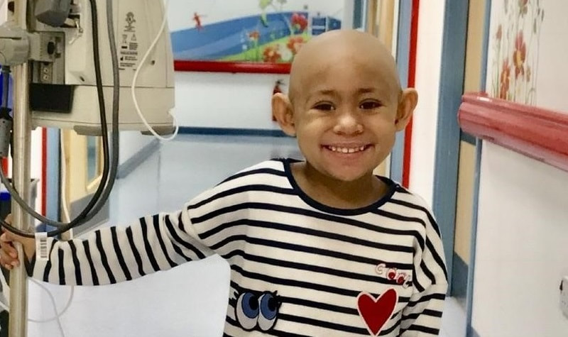 Young cancer patient_Maya Nash_in hospital receiving treatment_smiling to the camera_Mitchells Miracles_UK Neuroblastoma childrens cancer charity